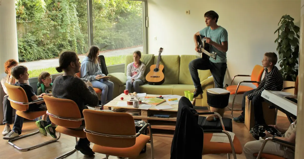 A music group listening to a guitar teacher