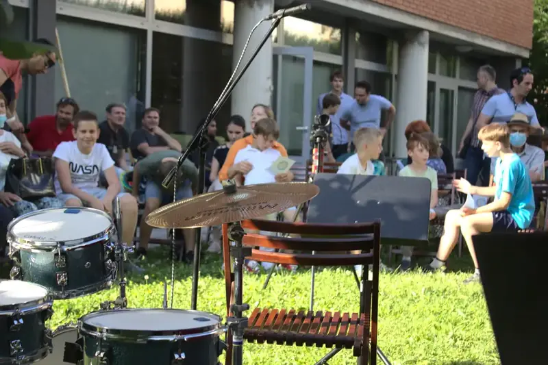 Children making music with adults in a garden